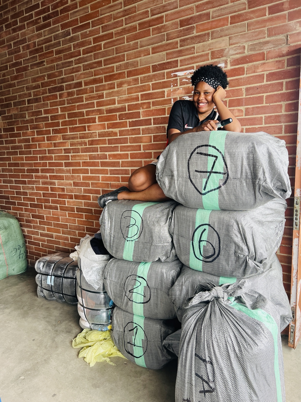 BeautyOasis founder sitting on thrift bales
